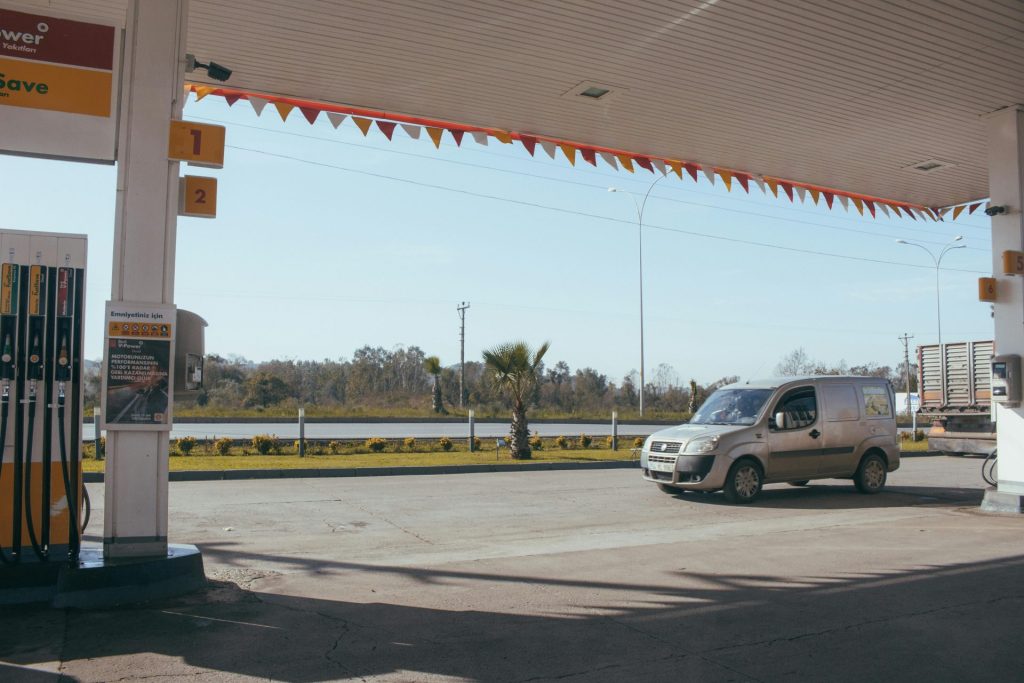 Ein Transporter, der an einer Tankstelle am Straßenrand unter einem klaren, blauen Himmel geparkt ist.